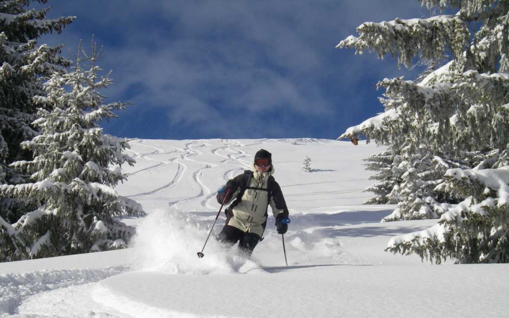 Skiers enjoying a sunny day on the slopes of Les Gets, surrounded by snowy mountains.