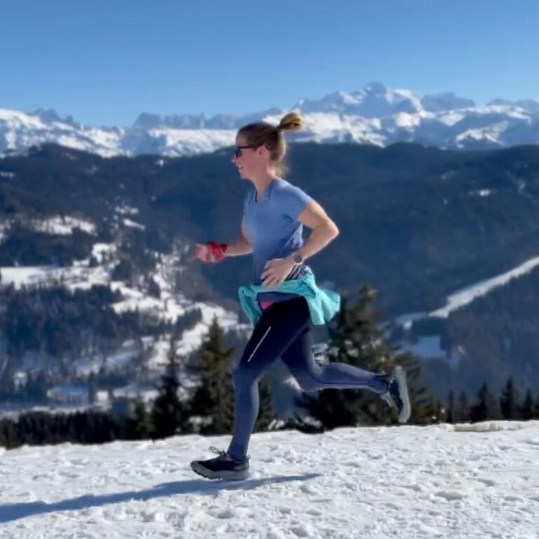 Woman trail running on a snow-covered track with Mont Blanc in the background.