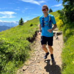 Man trail running on Mont Chery in Les Gets, enjoying panoramic views of the Alps.