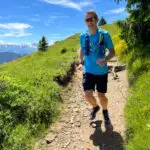 Man trail running on Mont Chery in Les Gets, enjoying panoramic views of the Alps.