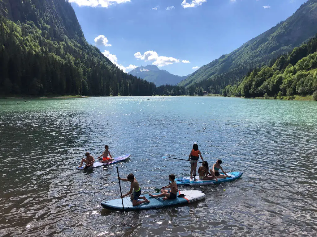 Scenic view of Lac Montriond in Morzine, showcasing crystal-clear water surrounded by lush green mountains.