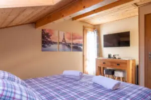 Cozy interior of Bedroom 2 Paris at Chalet Aventure in Les Gets, featuring a double bed and a single bed
